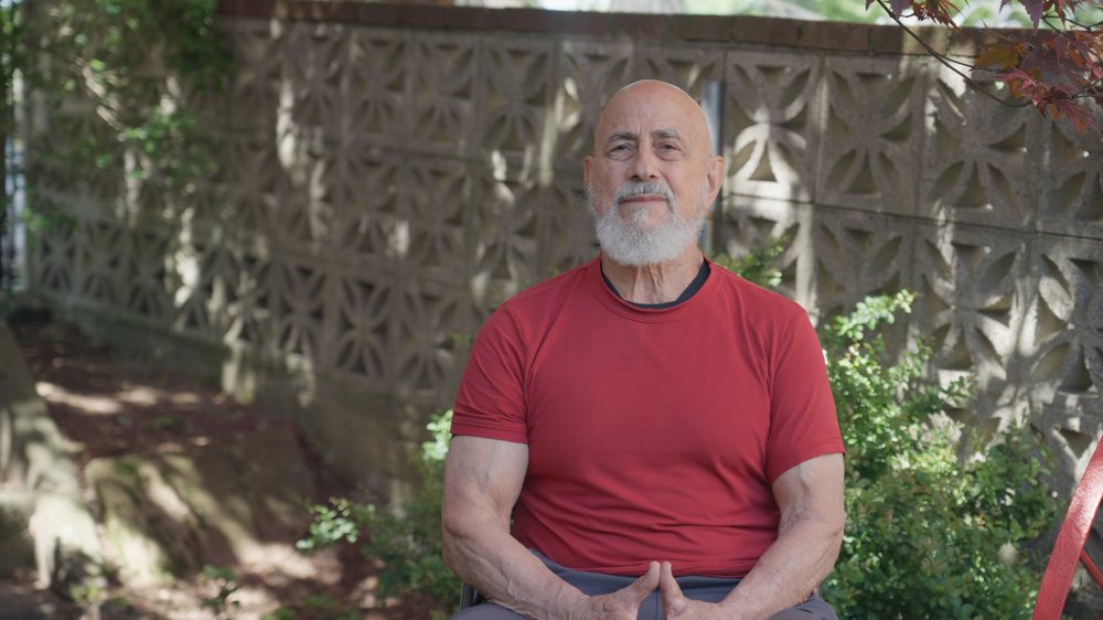 Jacinto, seated outdoors in a red shirt